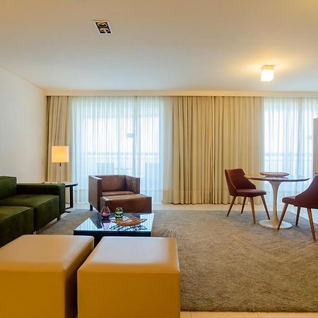 Hotel Luzeiros Sao Luis Eksteriør billede The photo depicts a modern and well-lit living space. It features a green sectional sofa and a brown armchair, with a small glass coffee table in front. There are two brown chairs around a circular table, providing a cozy dining or meeting area. The 
