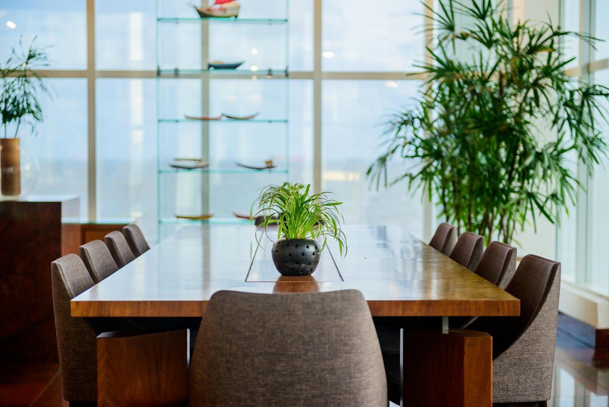 Hotel Luzeiros Sao Luis Eksteriør billede The photo shows a modern dining area featuring a long wooden table surrounded by upholstered chairs. In the center of the table, there is a small potted plant. Behind the table, large windows allow natural light to fill the space, and there are shelv