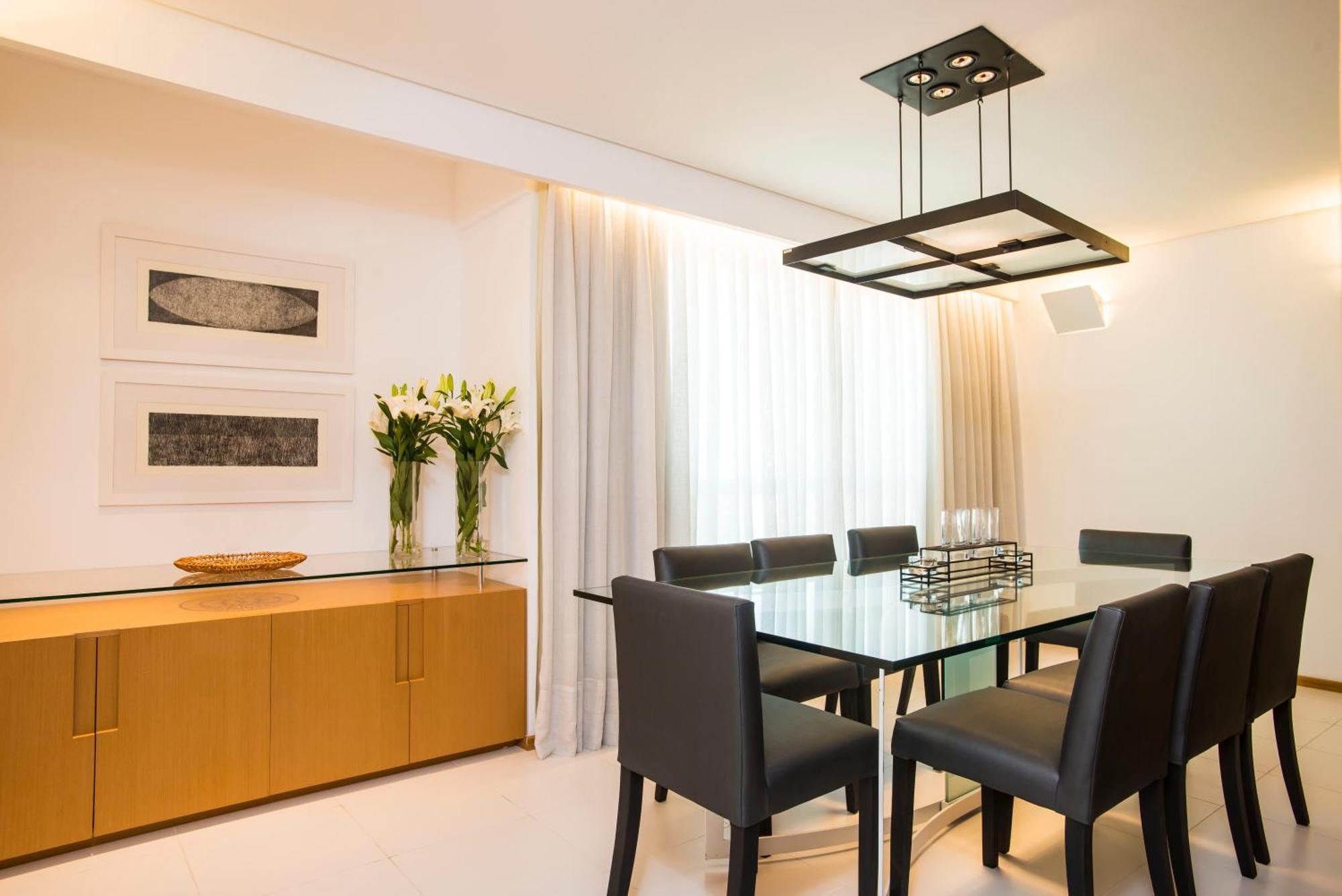 Hotel Luzeiros Sao Luis Værelse billede The photo shows a modern dining room with a sleek design. In the center, there is a glass dining table surrounded by six black chairs. Above the table, there is a contemporary pendant light that has a square design. The walls are adorned with two abs